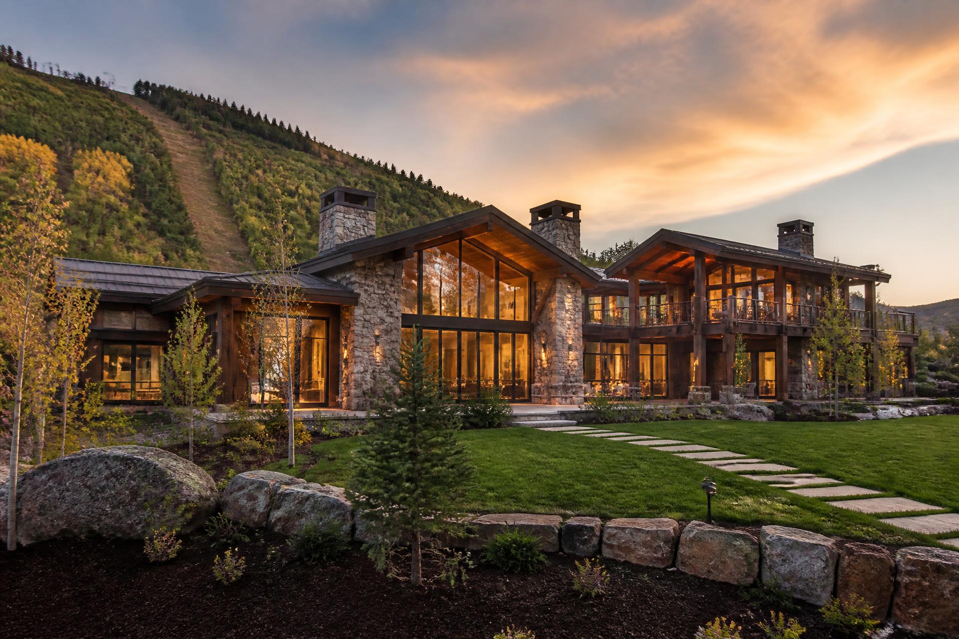 Luxury Park City mountain residence at golden hour with warm interior lighting
